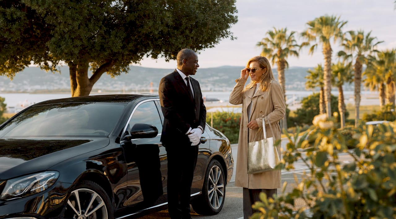 Professional chauffeur assisting traveler by luxury car
