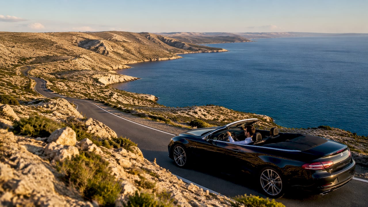Car driving along winding coastal road by sea