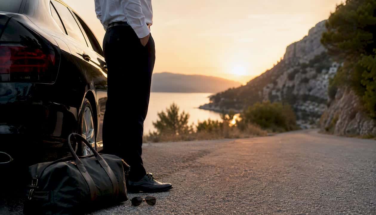 Private transfer driver opening a car door by the coast