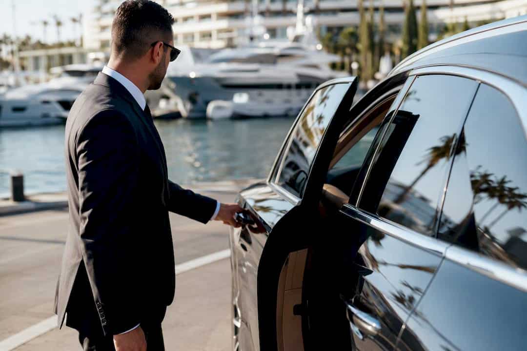 Chauffeur opening luxury vehicle door at airport