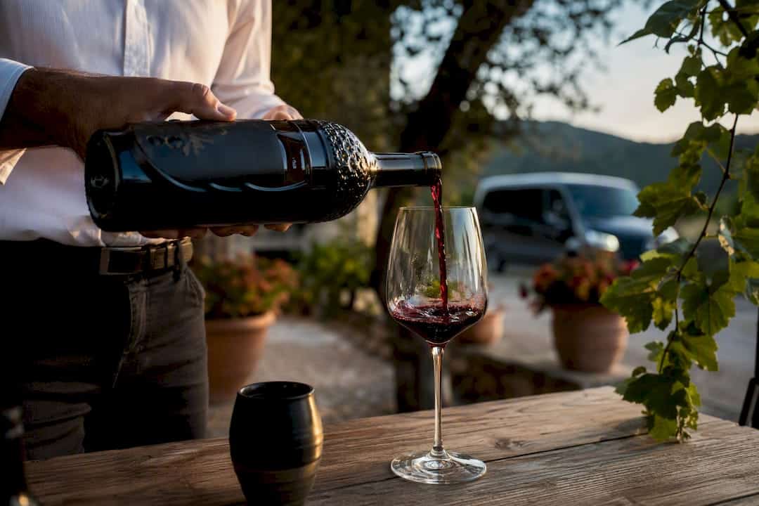 Pouring red wine overlooking Pelješac vineyards