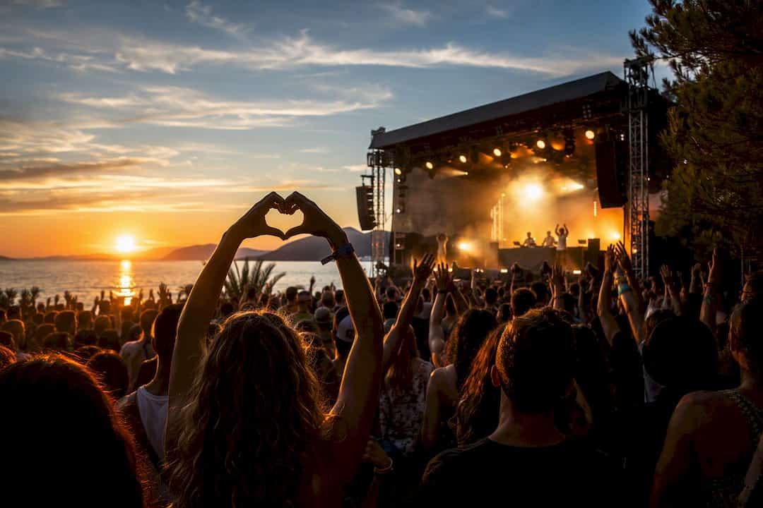 Festival crowd facing coastal sunset stage